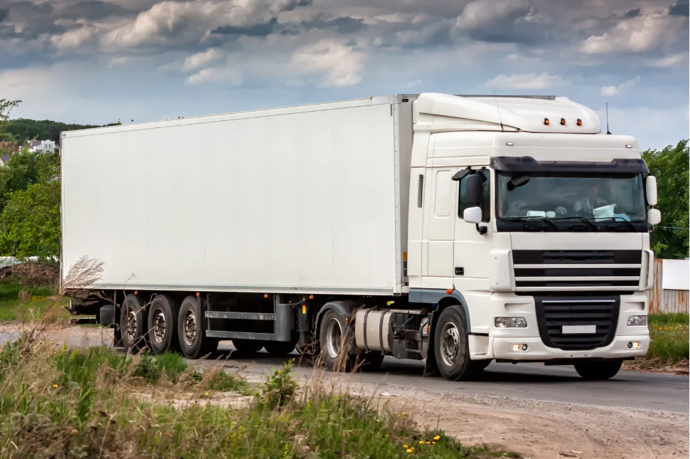White semi-truck with a cargo trailer on a country road
